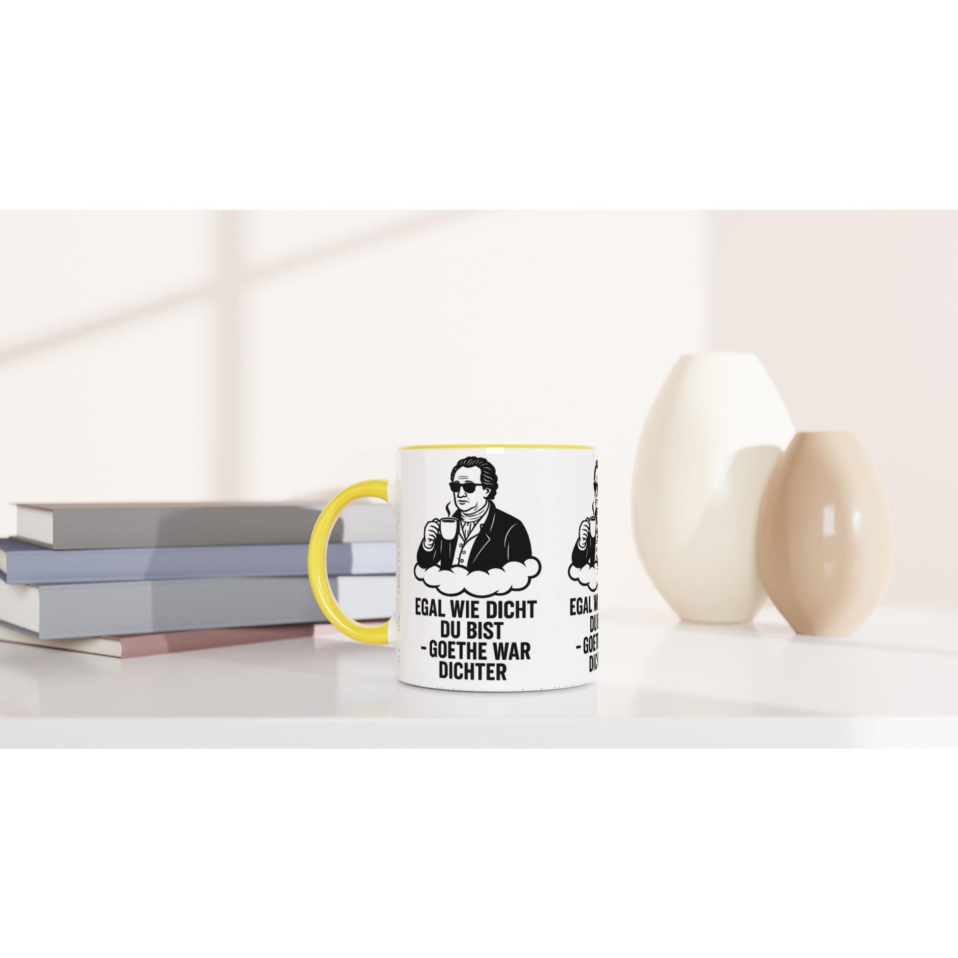 Witzige Geschenkidee Kaffeetasse mit Goethe Zitat und gelbem Henkel auf weißem Tisch