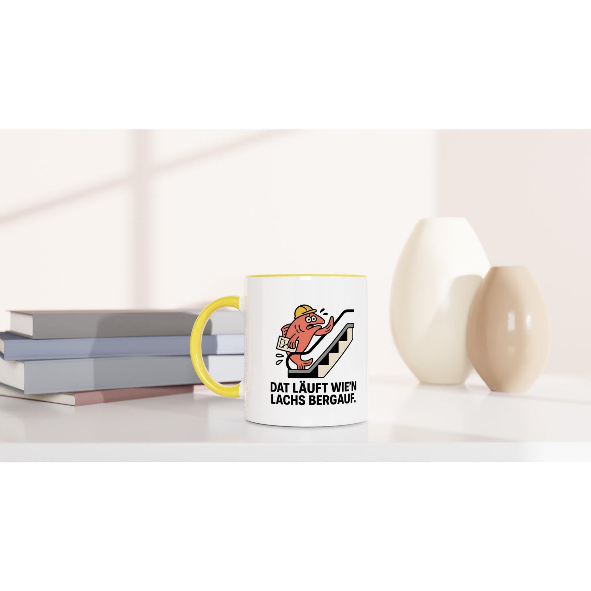 Lustige Tasse mit Spruch Dat läuft wie'n Lachs bergauf und gelbem Henkel auf weißem Tisch